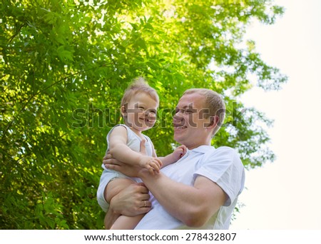 Father dad parent holding baby boy outdoors in summer garden