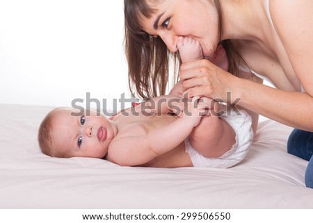 Cute happy family mother and baby on white background, Focus on woman\'s face, mom kissing and holding kids foot