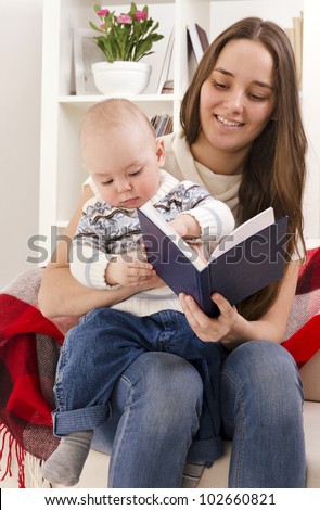 Young mother reads to the small son the book, sitting on a sofa