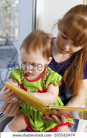 the little girl considers pictures in the book with her mom