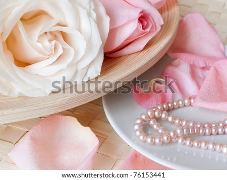 Two beautiful roses on a bamboo plate and pearls