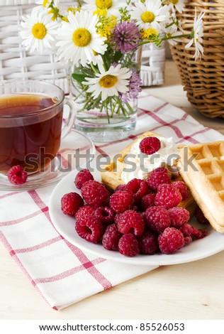 Composition with a tea cup, a raspberry and a bouquet of wild flowers