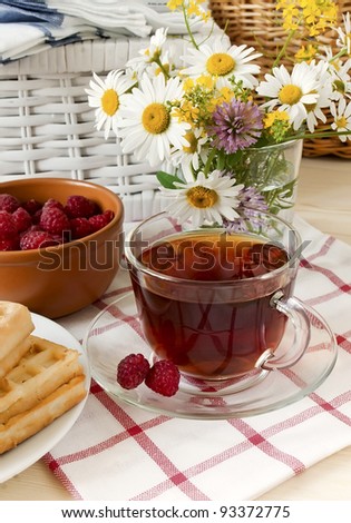 Composition with a tea cup, a raspberry and a bouquet of wild flowers