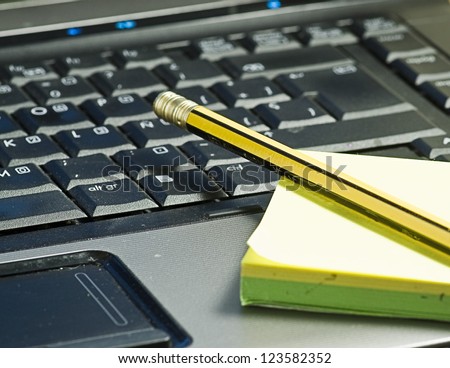 closeup of a computer with a pencil and post it
