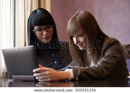 two women work with laptop in coffee