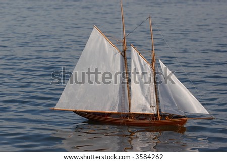 sailing ship model on blue water sail to the right