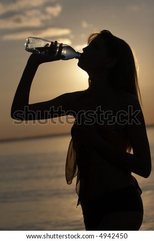 silhouette of girl drink water on water/sky background