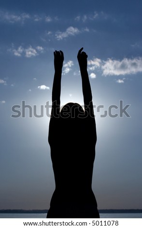silhouette of girl with hands raised up on sunset sky background