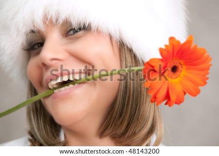 woman in fluffy fur cap hold flower in teeth