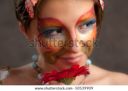 girl with butterfly make-up on face and flower look right