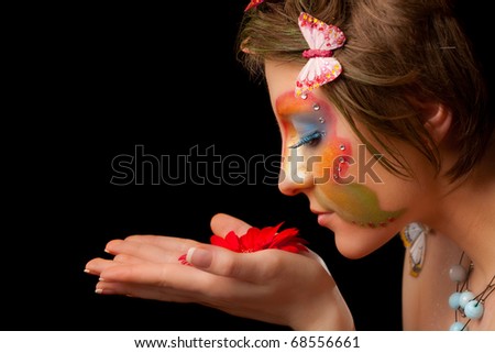 girl with butterfly make-up on face look on flower