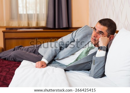 Tired businessman lying in bed and thinking