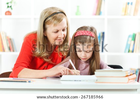 Grandmother helping little girl to learn to write