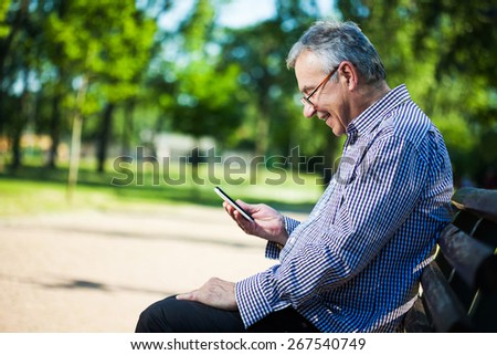 Senior man using digital tablet in park