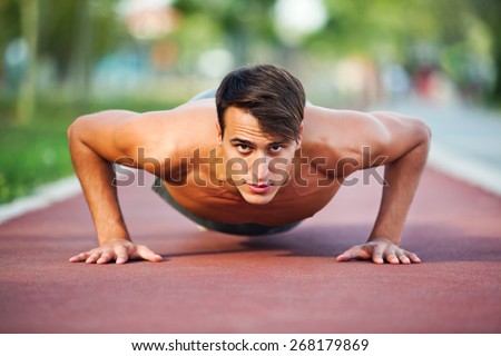 Young man exercising outdoor, doing push-ups