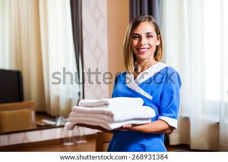 Happy hotel maid holding towels