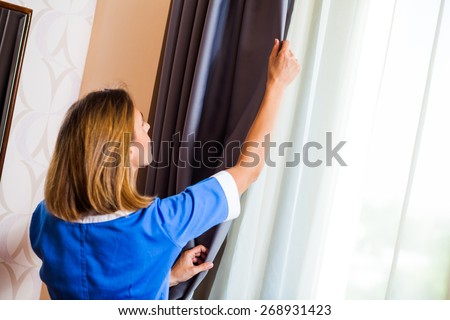 Hotel maid fixing the curtain