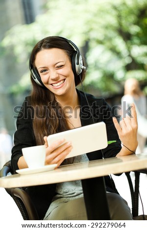 Young woman surfing the net and listening music on digital tablet in a cafe