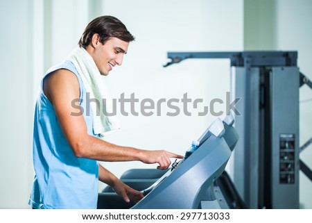 Happy man adjust treadmill in gym