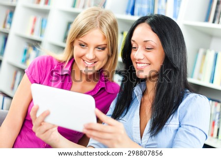 Students learning in library, using digital tablet