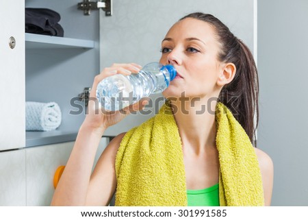 Girl drinking water in locker room after fitness training