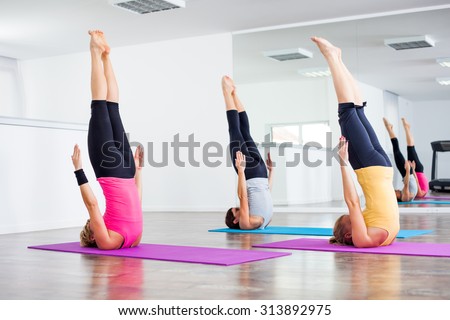Three girls practicing yoga, Yoga-Sarvangasana/Shoulder stand pose