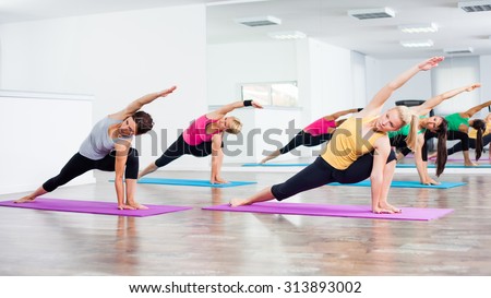 Four girls practicing yoga, Vasisthasana/Half side plank pose