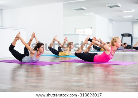 Three girls practicing yoga, Yoga - Dhanurasana/Bow pose