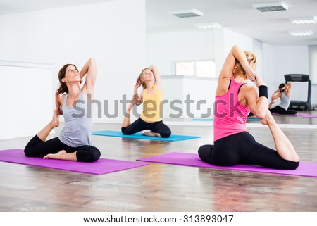 Three girls practicing yoga, Eka pada Rajakapotasana / Pigeon pose