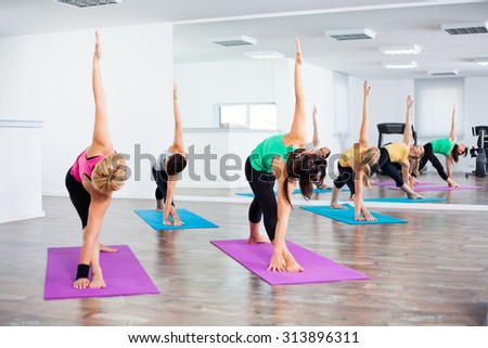 Four girls practicing yoga, Yoga Trikonasana Bikram/Bikram triangle right pose