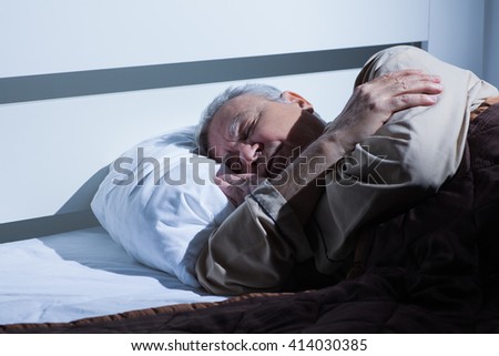 Senior man is sleeping in his bed.