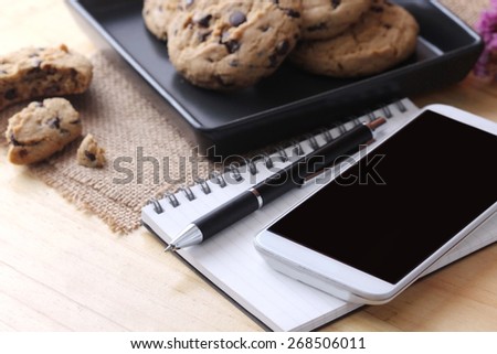 notebook on desk with coffee biscuit and pen,Office concept