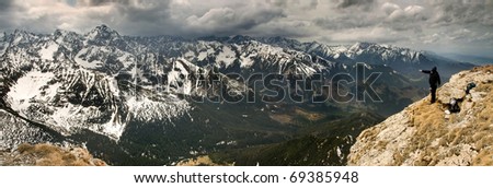 Man shows mountains. Panorama of high snow mountains and long walley. Slovakian Tatra Mountains.