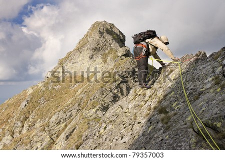 Man in a hood with backpack, harness and a rope climbing in mountains. Tatra Mountains.