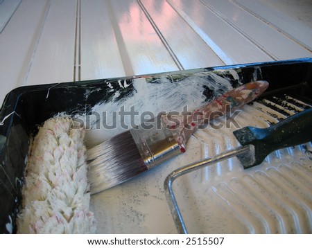 painted surface with paint tray roller and brush in foreground