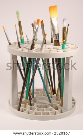 Various sized paint brushes in a paint brush holder on a white background