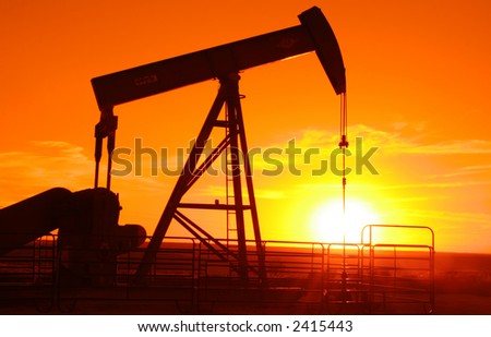 Oil field pump jack with a setting sun behind it