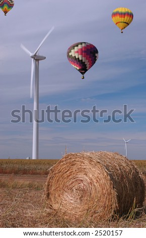 Three hot air balloons flying over a wind farm and sorghum field in Texas