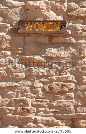 women sign on side of stone wall