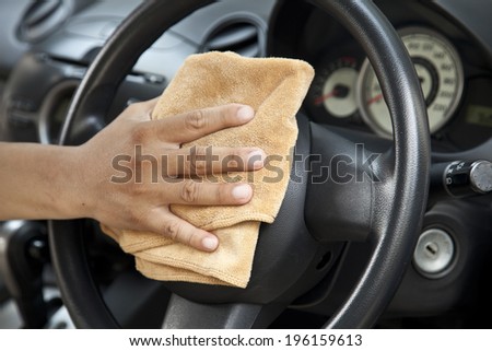 hand with microfiber cloth polishing steering wheel