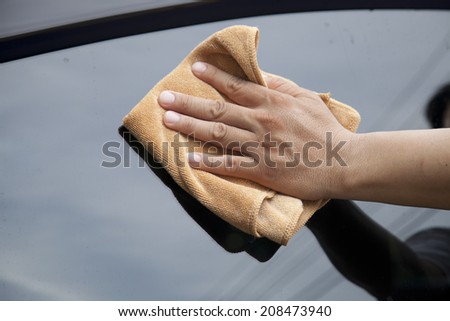 Hand with microfiber cloth cleaning car.