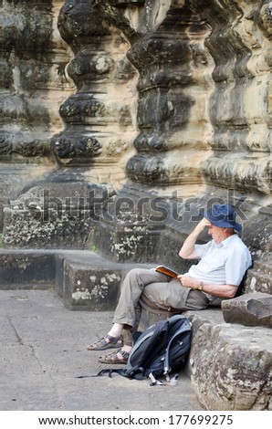 Preah Vihear Temple,Cambodia-Oct 21,2012 :Unidentified tourist sit on stone reading guide book on October 21,2012 in Preah Vihear Temple Cambodia.