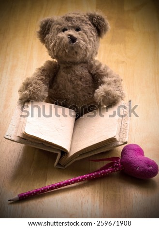 Close up Teddy bear hold blank mulberry book sit on wooden floor wait for someone to write something with pink pen ,photo in grunge vintage style