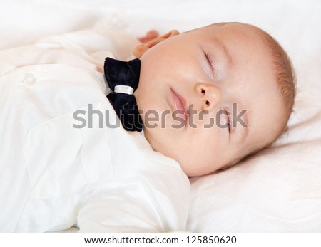 Baby boy dressed for party sleeping peacefully.