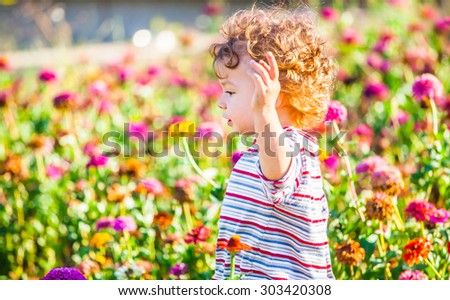 Portrait of 1 year old baby boy admiring the flowers in the garden on a sunny afternoon.