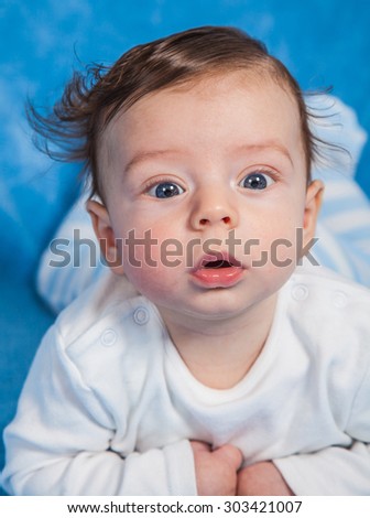 Portrait of an adorable baby boy on a blue blanket.