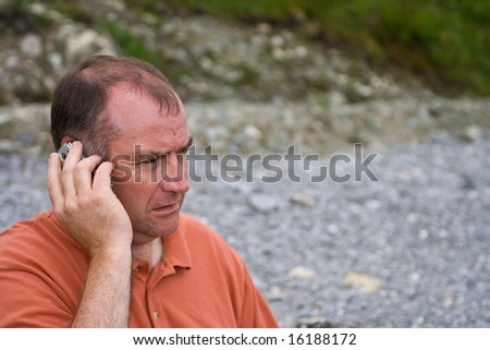 Middle aged man speaking on the phone outdoors.