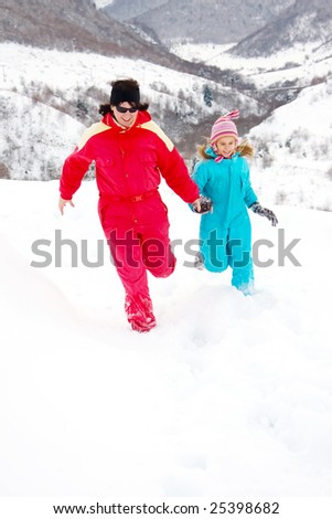 Mother and daughter running through the snow.