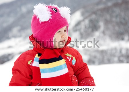 Toddler girl dressed in red having fun in the snow.