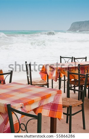 Tables from a tavern at Zakros in Crete, in a windy day with big waves, Greece